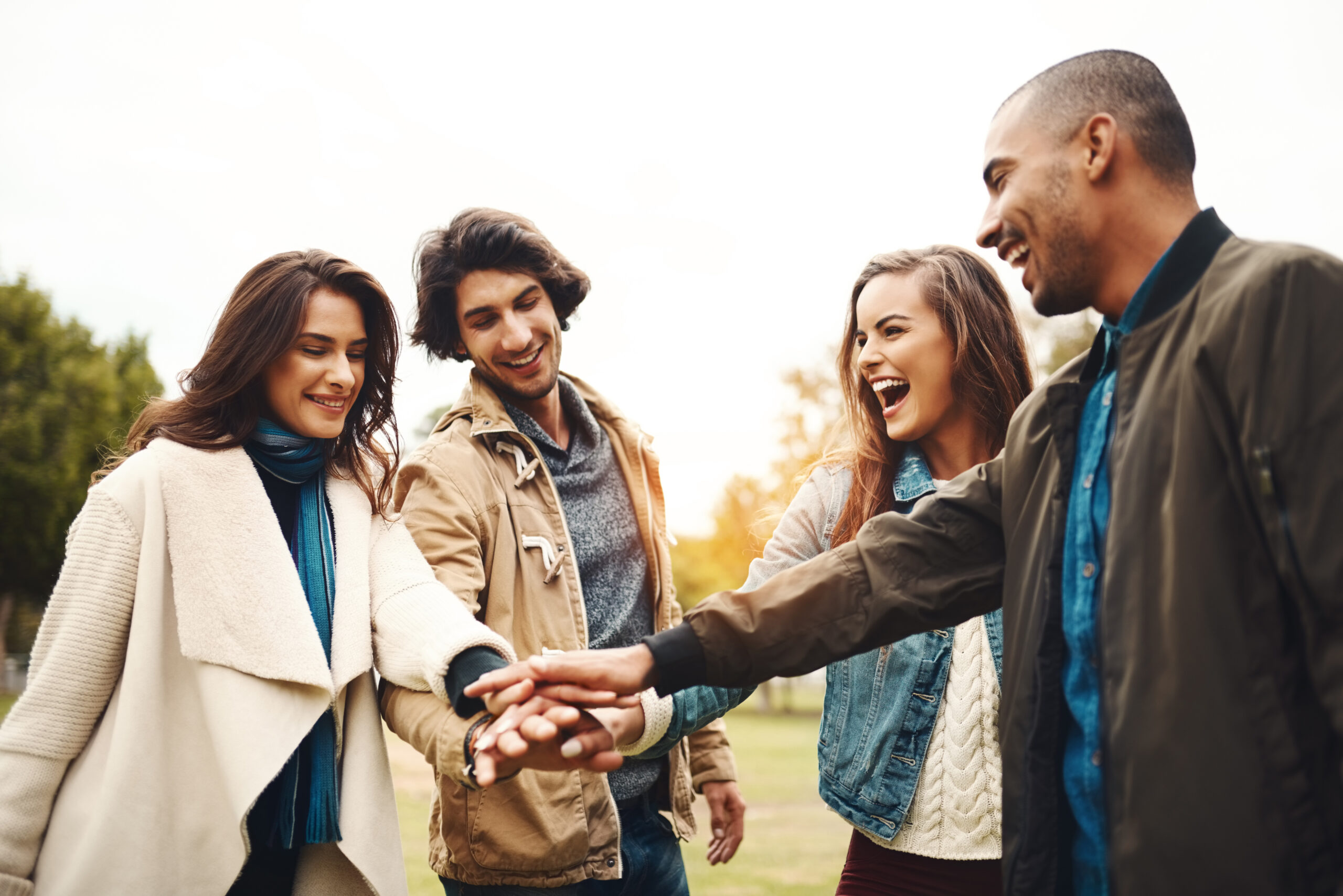 On The Count Of Three. A Group Of Cheerful Young Friends Forming A Huddle With Their Hands Together Outside During The Day.